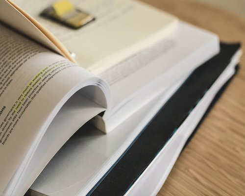 Thick academic textbooks and study guides stacked on a table